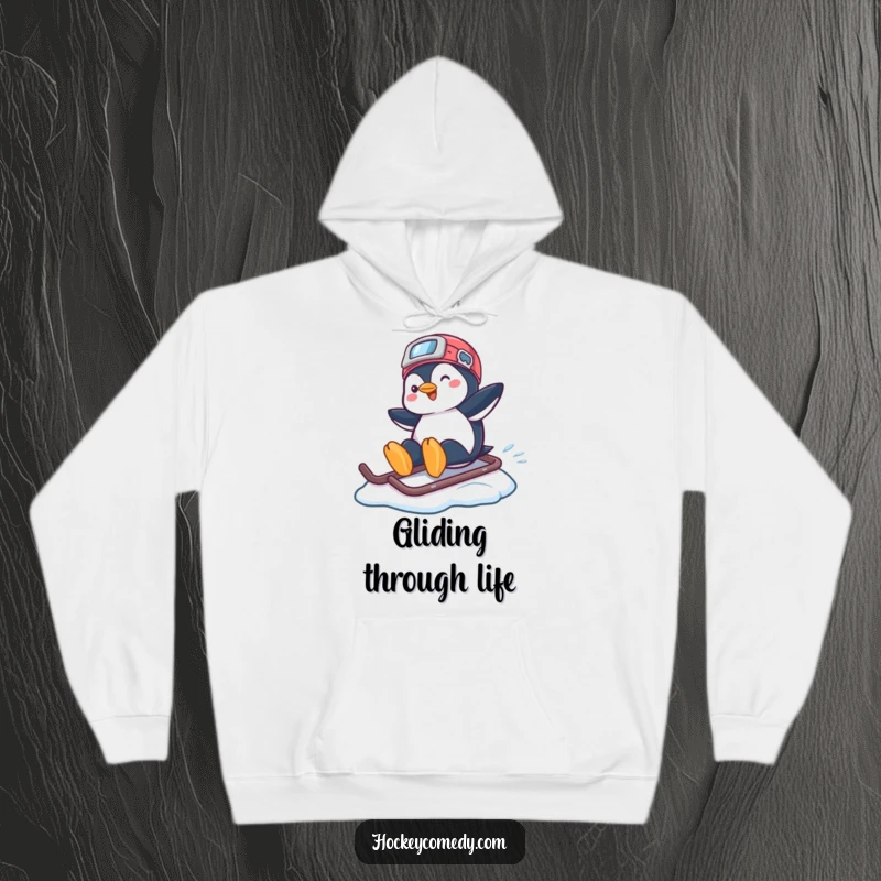 Funny hoodie showing a playful penguin sliding across ice, using a hockey helmet as a snowboard, radiating cool vibes.