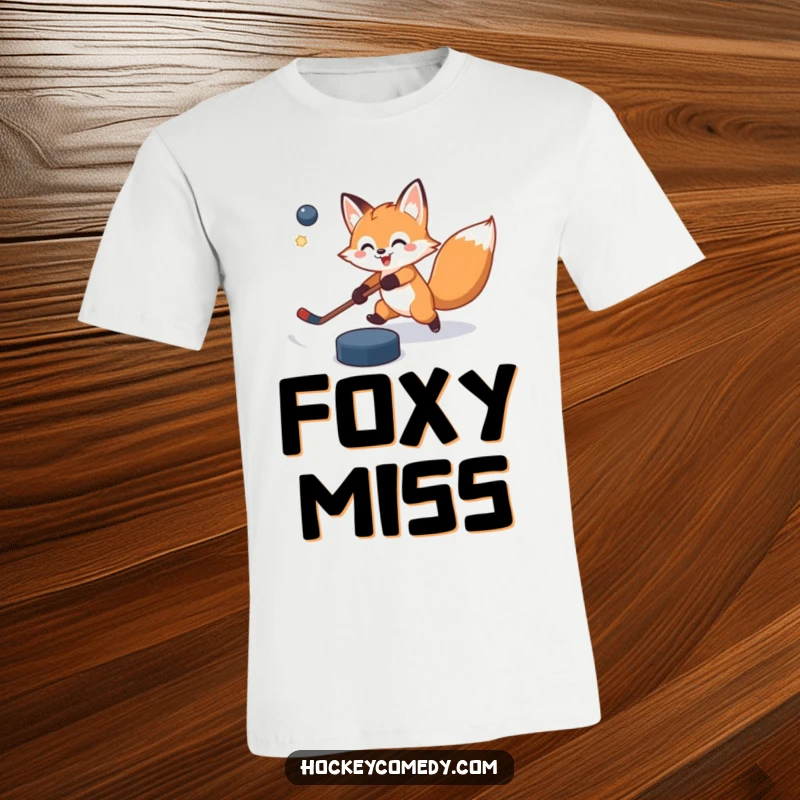 Funny t-shirt showcasing a cheerful fox attempting a powerful slap shot, with the puck flying comically off course, highlighting determination.