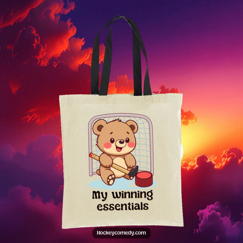 Funny tote bag with a happy bear cub playfully swatting a hockey puck into a net, ready for game day adventures.